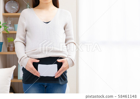 Pregnant woman putting disposable warmers on stomach Pregnant woman putting disposable warmers on stomach 58461148
