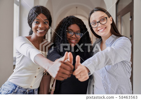 Three happy mixed-race female students showing thumbs up Three happy mixed-race female students showing thumbs up 58463563