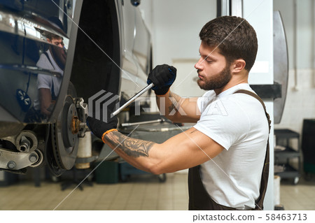 View from side of handsome man changing tire of car 58463713