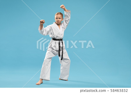 Girl in kimono with black belt practising karate. 58463832