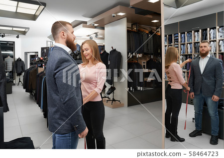 View form side of man wearing new grey jacket in boutique 58464723