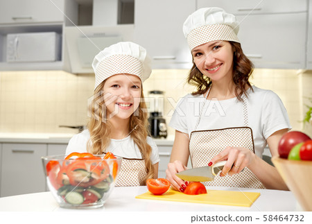 Cheerful family looking at camera while cooking salad Cheerful family looking at camera while cooking salad 58464732