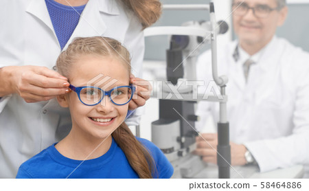 Front view of girl wearing new glasses in optical store 58464886