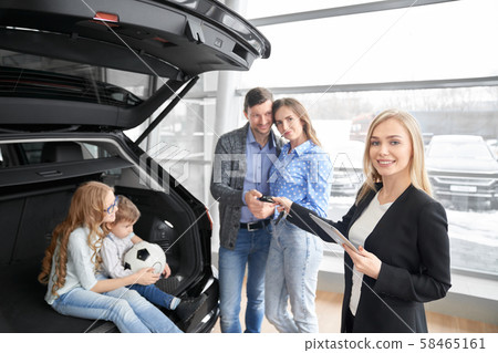 Car seller looking at camera and giving keys of car clients 58465161