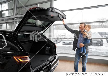 Father holding son and looking at capacious trunk of auto Father holding son and looking at capacious trunk of auto 58465173