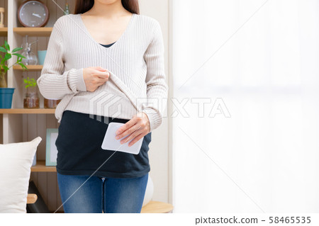 Pregnant women trying to paste disposable warmers on their stomachs Pregnant women trying to paste disposable warmers on their stomachs 58465535