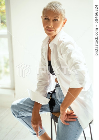 Cute blonde sitting on the chair and looking aside at wall 58466824