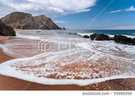 Praia da Adraga at atlantic ocean, Portugal. Foamy wave at sandy beach with picturesque landscape 58466999