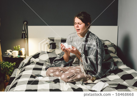 sick woman with runny nose, sitting in bed. woman feeling unwell and sneeze bedroom. Woman holding 58468668