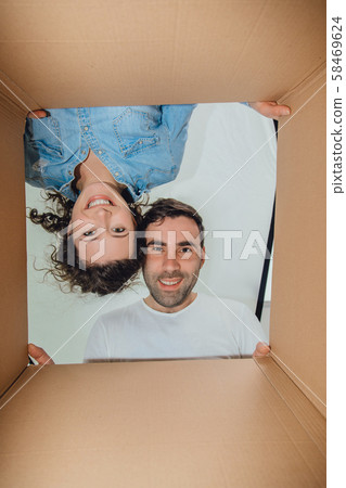 Curious wife and husband unpacking carboard boxes. 58469624