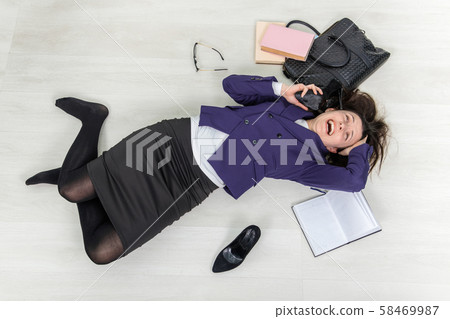 Young teacher is looking out of mind, lying on thr floor, holding her shoe near ear, as if it was Young teacher is looking out of mind, lying on thr floor, holding her shoe near ear, as if it was 58469987