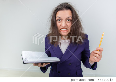 Insane young teacher with tousled hair, holding notebook and pen, setting her teeth, looking out of Insane young teacher with tousled hair, holding notebook and pen, setting her teeth, looking out of 58470018