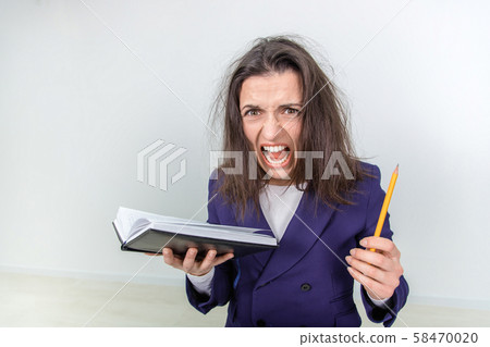 Exhausted young teacher with tousled hair holdingnotebook and pen, leaning to the camera, screaming Exhausted young teacher with tousled hair holdingnotebook and pen, leaning to the camera, screaming 58470020