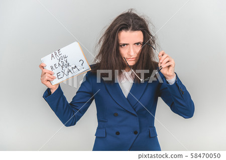 Totally tired young teacher is standing, holding a sheet of paper with ready for exam written on it Totally tired young teacher is standing, holding a sheet of paper with ready for exam written on it 58470050