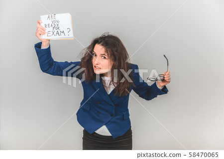 Totally tired young teacher is standing, holding a sheet of paper with ready for exam written on it 58470065