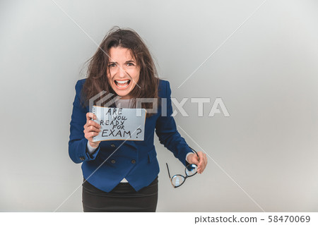 Totally tired young teacher is standing, holding a sheet of paper with ready for exam written on it 58470069