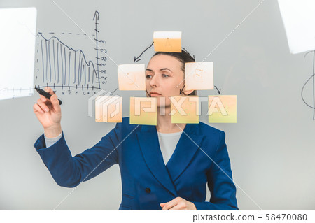 Inspired woman in formal suit, drawing diagram on the glass. 58470080