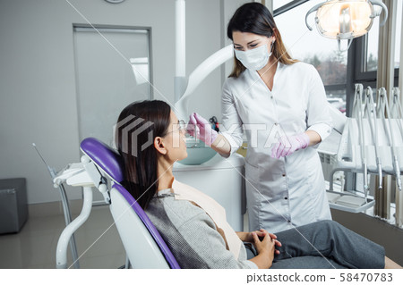 A woman is preparing for a dental examination. Woman having teeth examined at dentists.  58470783