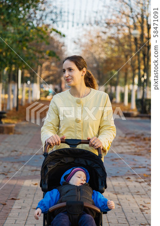 A woman with a child in a stroller walks through A woman with a child in a stroller walks through 58471091