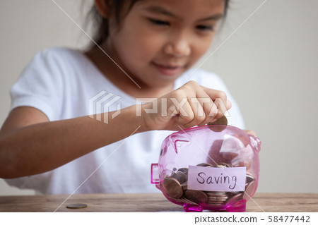 Cute asian child girl putting money into piggy bank  58477442