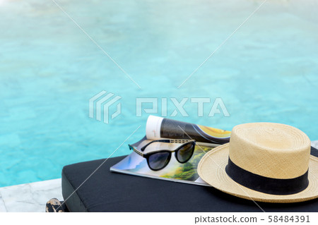 Book and hat on the sun bed near the swimming Book and hat on the sun bed near the swimming 58484391