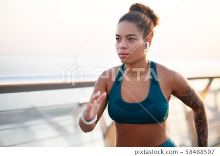 Woman wearing earphones listening to music and running Woman wearing earphones listening to music and running 58488507