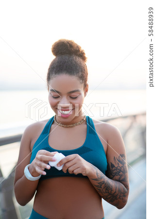 Cheerful woman putting her earphones into box after running Cheerful woman putting her earphones into box after running 58488939