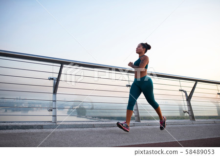 Dark-skinned woman wearing leggings enjoying morning run Dark-skinned woman wearing leggings enjoying morning run 58489053