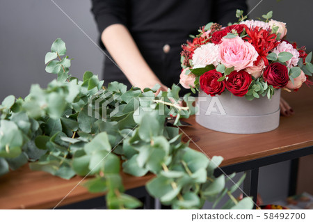 Florist woman creates flower arrangement in a round box. Beautiful bouquet of mixed flowers. Floral 58492700