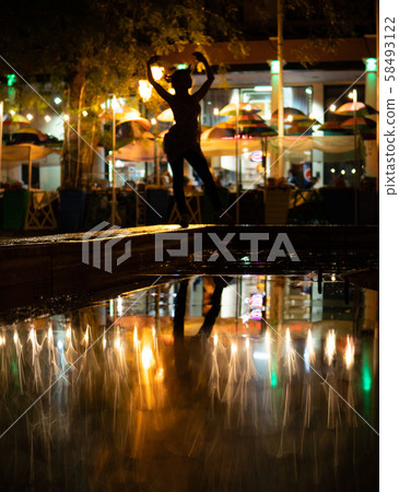 Bokeh backlight girl silhouette after rain on the street at night 58493122