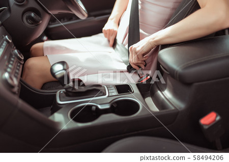 woman fastens seat belt in car, right-hand drive, left-hand traffic in passenger compartment woman fastens seat belt in car, right-hand drive, left-hand traffic in passenger compartment 58494206