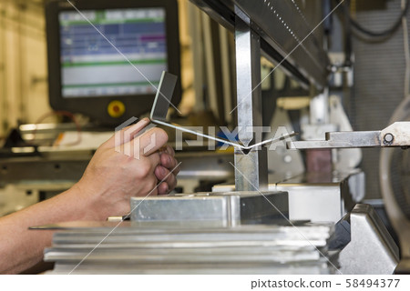 worker operating metal press machine at workshop. 58494377