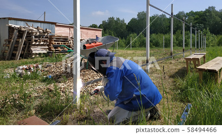 A fence installer welds a metal profile to a new 58494466