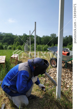 At the construction site, the master welds a metal 58494471