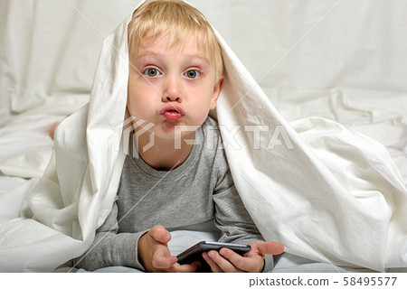 Little blond boy grimaces with a smartphone in his 58495577