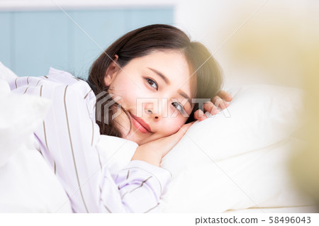 Woman in bed lying on pillow 58496043