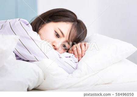 Woman in bed lying on pillow Woman in bed lying on pillow 58496050