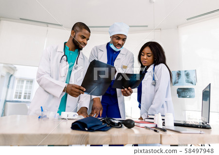 radiology, people and medicine concept - group of three African doctors, surgeon and radiologists radiology, people and medicine concept - group of three African doctors, surgeon and radiologists 58497948