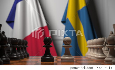 Flags of France and Sweden behind pawns on the chessboard. Chess game or political rivalry related Flags of France and Sweden behind pawns on the chessboard. Chess game or political rivalry related 58498013