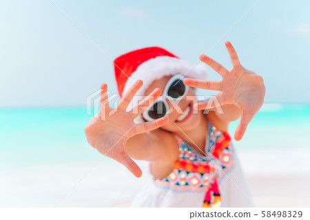 Adorable little girl in Santa hat on tropical beach Adorable little girl in Santa hat on tropical beach 58498329