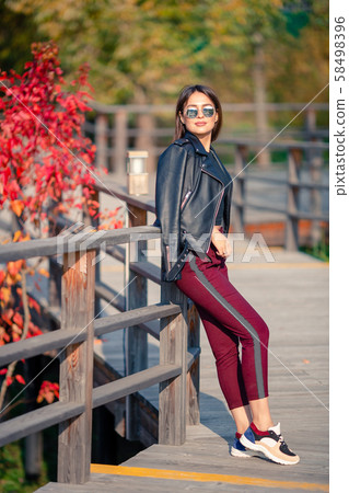 Fall concept - beautiful woman drinking coffee in autumn park under fall foliage Fall concept - beautiful woman drinking coffee in autumn park under fall foliage 58498396