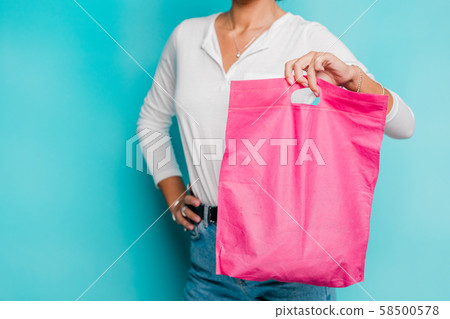 Mid-section of casual young female in white polo shirt and blue jeans with bag 58500578