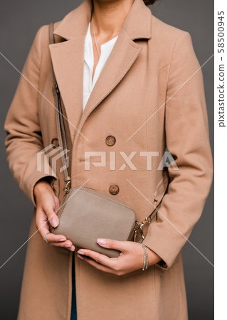 Young elegant lady in stylish brown coat holding small leather handbag Young elegant lady in stylish brown coat holding small leather handbag 58500945