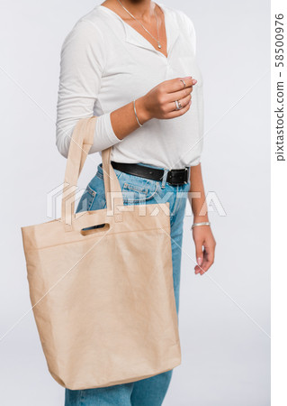 Young casual woman in white polo shirt and blue jeans carrying tote bag 58500976