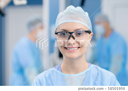 Young successful female assistant or surgeon in protective eyewear and uniform 58501950