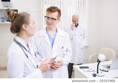 Two young colleagues in whitecoats discussing medical stuff in clinics 58501966