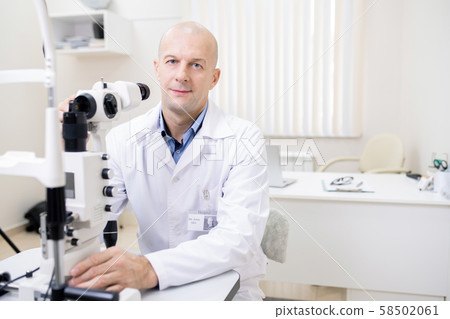 Successful professional optometrist working with new eyesight check-up equipment Successful professional optometrist working with new eyesight check-up equipment 58502061