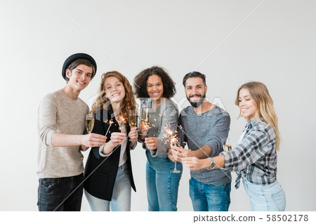 Cheerful friends toasting with flutes of champagne and holding bengal lights Cheerful friends toasting with flutes of champagne and holding bengal lights 58502178