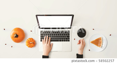 Person using a laptop computer with pumpkins Person using a laptop computer with pumpkins 58502257