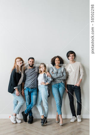 Group of cheerful young affectionate friends in jeans and pullovers 58502298